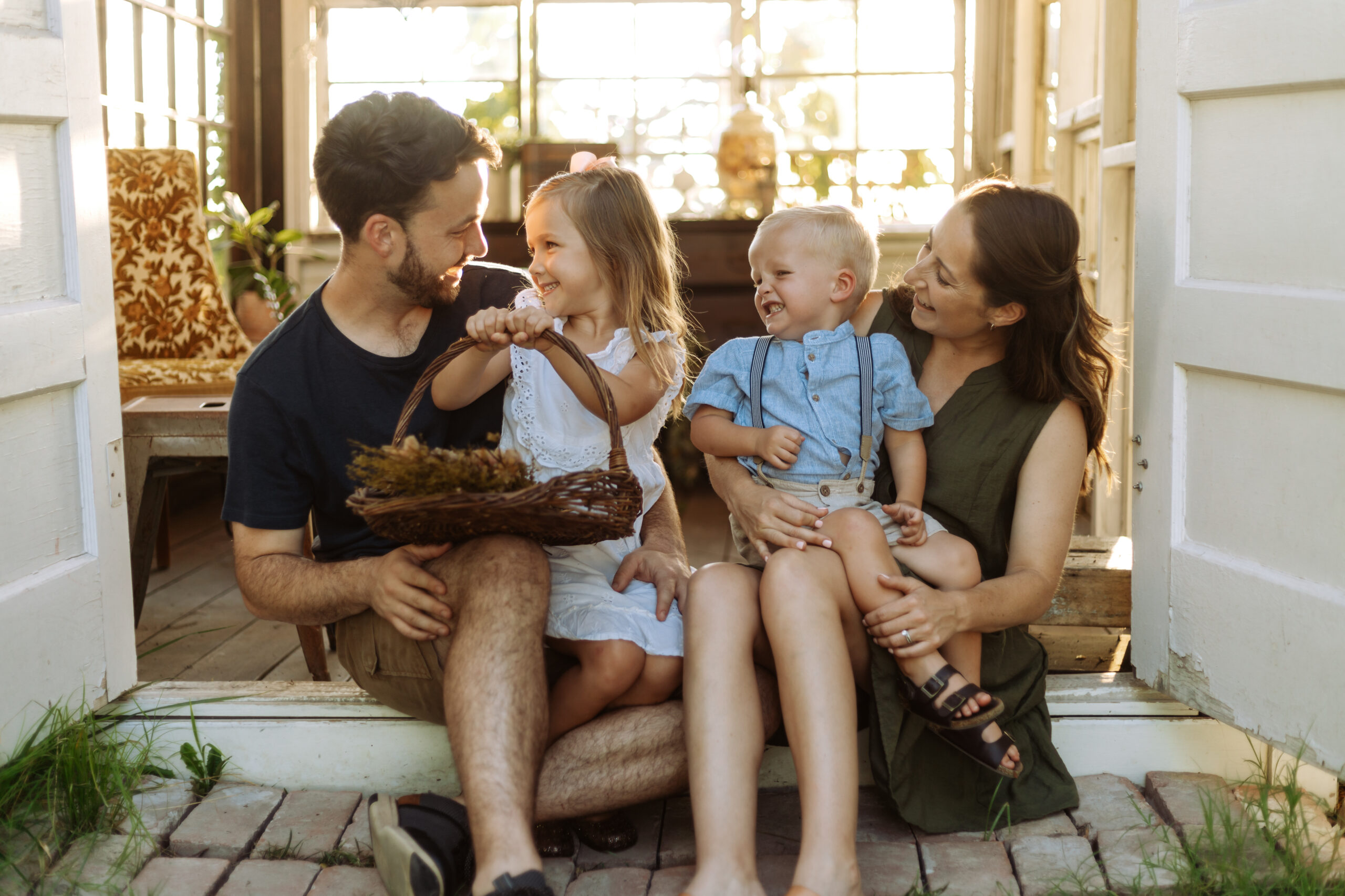 Children and Parents smiling with golden light behind them. Girl is holding a basket.